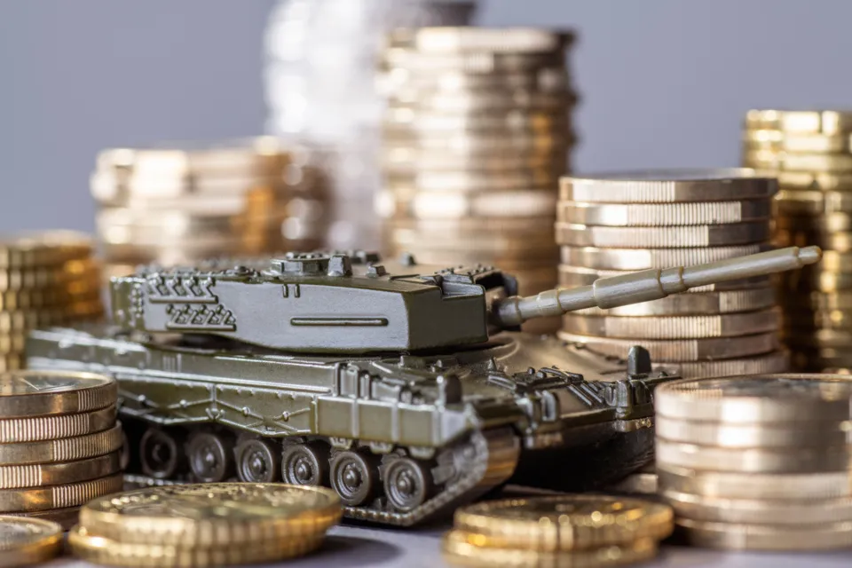 En leksakspansarvagn som står på en hög med mynt.