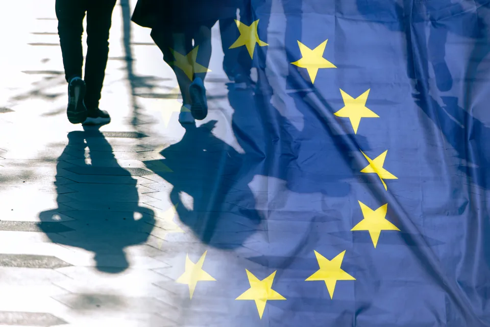 Personer som går med transparent EU-flagga i förgrunden.